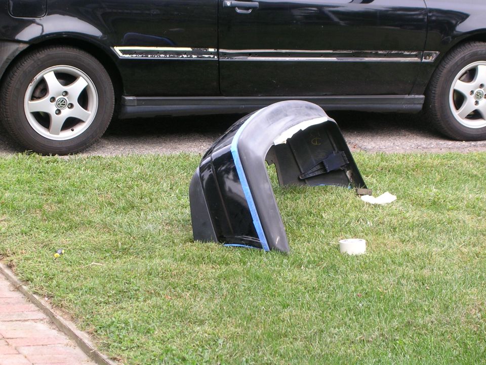 black car bumper on grass next to a black car