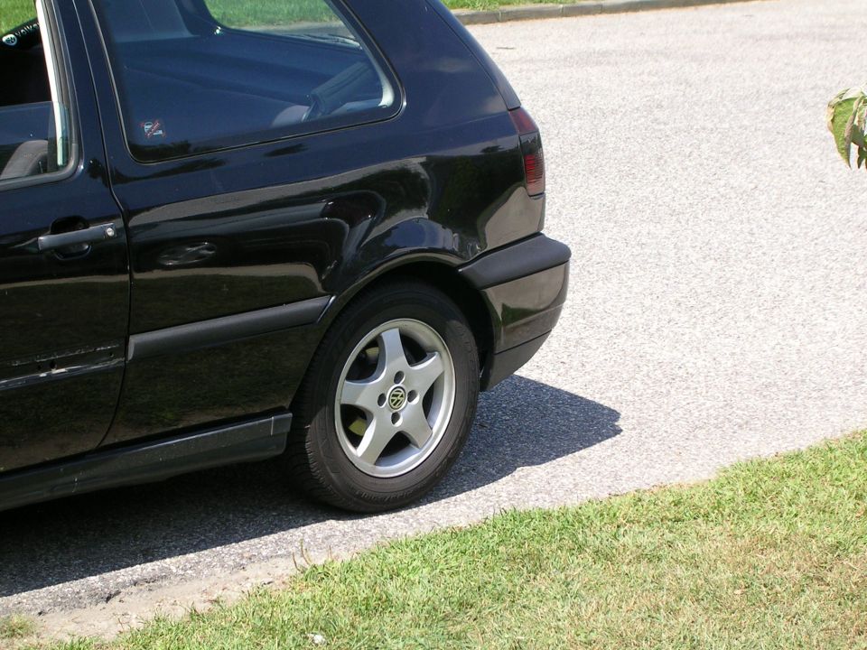 Black Volkswagen Golf GTI parked on street, rear quarter view