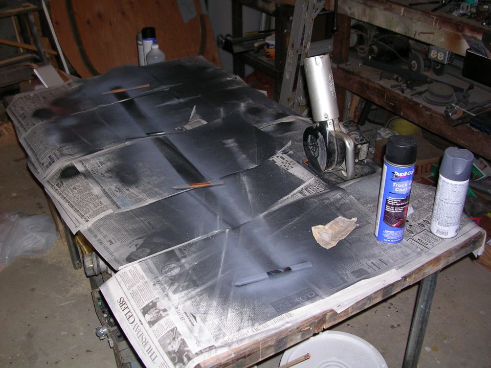 Car hood section covered in newspaper and being spray painted