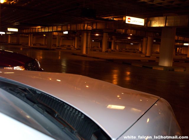 White car hood and windshield in a dimly lit parking garage