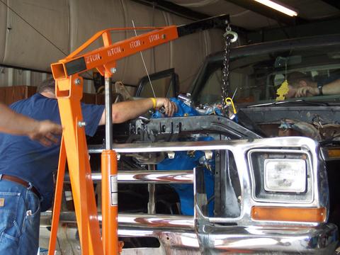 1979 Ford F-150 - Mechanics work on installing the engine of a 1979 Ford F-150 truck in a garage setting.
