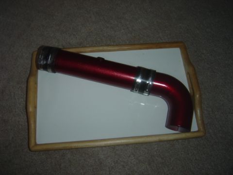 1998 Ford Taurus - A red metallic intake pipe with silver clamps is displayed on a white tray.
