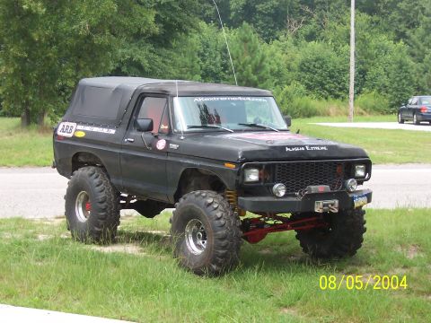 1978 Ford Bronco - A lifted black late-1970s Ford Bronco with a black soft top, off-road tires on chrome wheels, a front winch, coilover-style shocks, and 'Al…