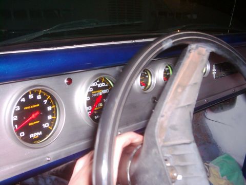 1978 Ford Bronco - Interior view of a vehicle's dashboard, showing aftermarket gauges and a hand operating the steering column.