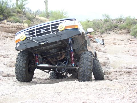 1994 Ford Bronco - This modified Ford Bronco is navigating a challenging rocky trail with significant suspension articulation.