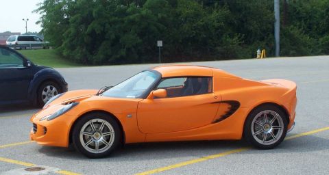1998 Ford Crown Victoria - Side view of an orange Lotus Elise sports car in a parking lot.