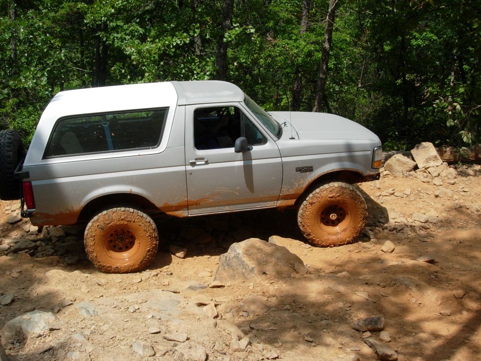Gray 1995 Ford Bronco with white top on a dirt trail, side view