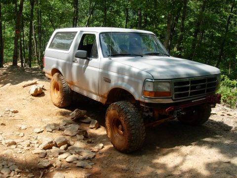1995 Ford Bronco - A white Ford Bronco navigates a rocky, wooded trail.
