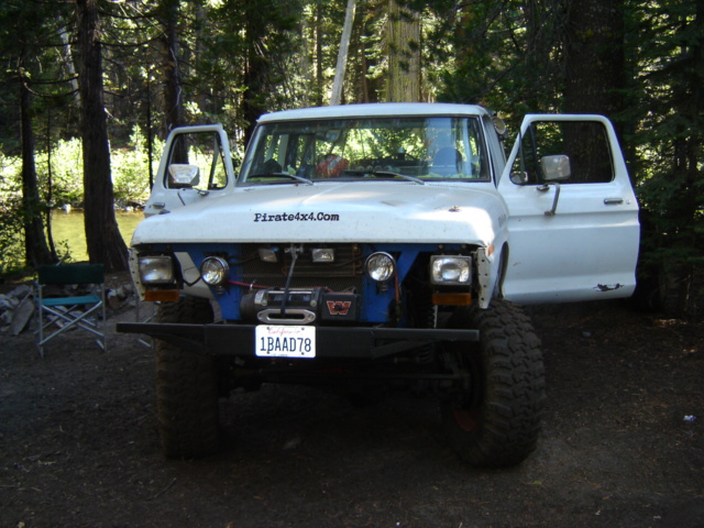 White early Ford 4x4 with 'Pirate4x4.Com' on hood, front winch and California plate, parked in woods