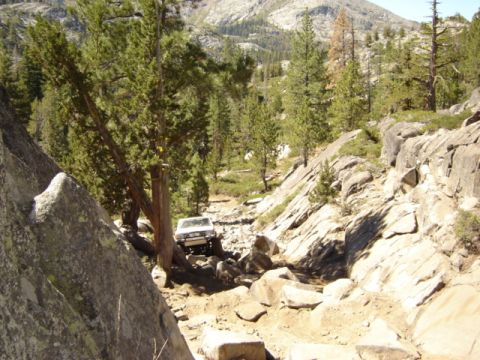 1991 Ford Bronco - A white SUV tackles a challenging, rocky terrain on an off-road trail.