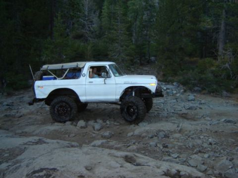 1991 Ford Bronco - This white Ford Bronco, likely a 1978 model, navigates a challenging rocky trail with its soft top deployed.