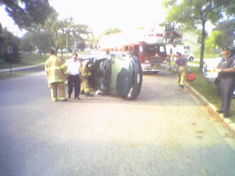 1993 Ford Bronco - Emergency responders attend to an overturned green SUV at the scene of an accident.