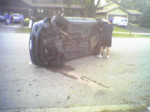 1993 Ford Bronco - A vehicle has overturned on a residential street, with its undercarriage exposed.