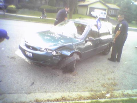 1993 Ford Bronco - A damaged green sedan sits on the roadside with police officers present.