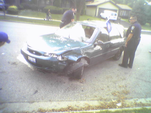 Green sedan with crumpled front end and deployed airbag