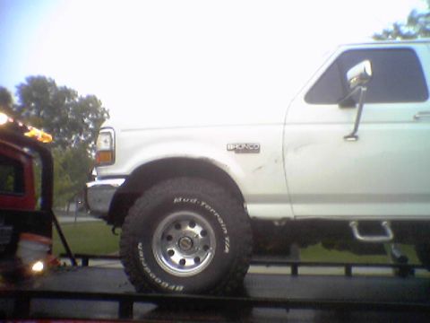 1993 Ford Bronco - A white 1993 Ford Bronco is being towed, with its side profile clearly visible.