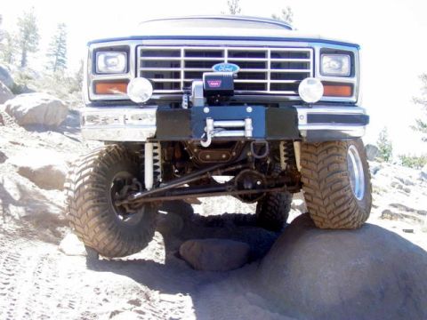 1986 Ford Bronco - This lifted Ford Bronco is navigating a rocky trail with its front tires on large boulders.