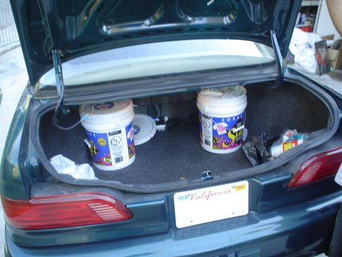 1993 Ford Taurus - The trunk of a dark green 1993 Ford Taurus contains two buckets and other items.