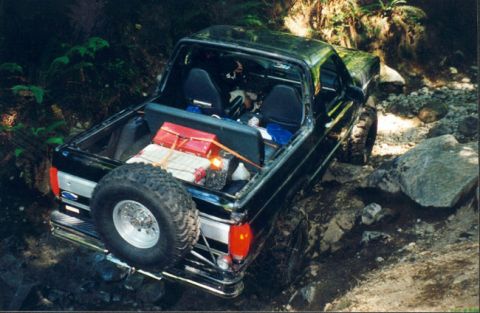 1993 Ford Bronco - A black Ford Bronco navigates a challenging rocky terrain, its rear tire mounted externally.