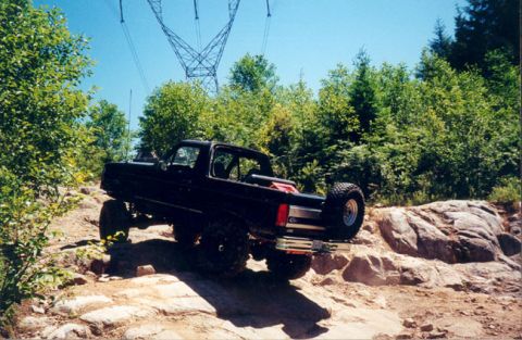 1993 Ford Bronco - This 1993 Ford Bronco navigates a challenging rocky trail under a clear blue sky.