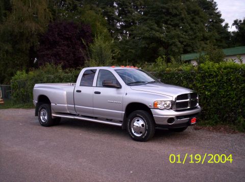 1983 Ford Bronco - This Dodge Ram pickup truck is parked in front of a line of trees and hedges.