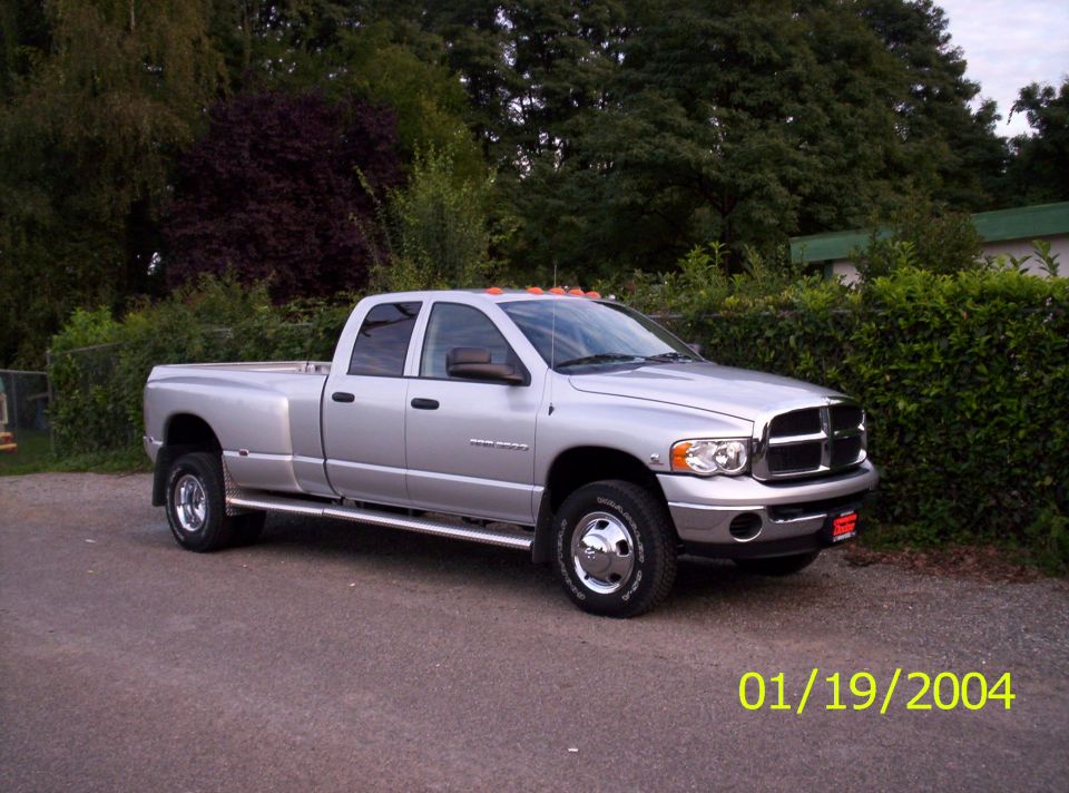 Silver four-door Dodge Ram pickup truck with dual rear wheels parked on asphalt