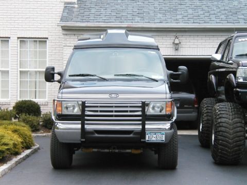 1994 Ford Bronco - Ford Econoline van with brush guard and large tires parked next to a lifted pickup truck.