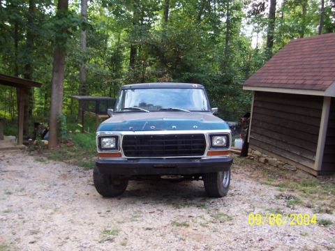 1979 Ford Bronco - A 1979 Ford F-150 pickup truck is shown in a rural setting with trees and a small building.