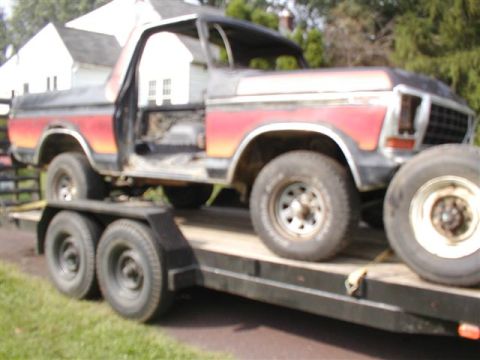 1979 Ford Bronco II - A Ford Bronco is being transported on a trailer, with its doors missing and showing signs of wear.