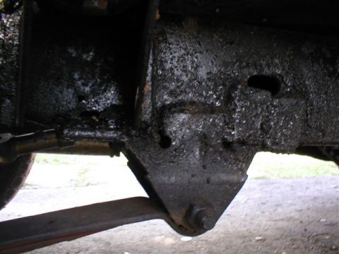 1979 Ford Bronco II - Close-up view of a vehicle's leaf spring and frame bracket, covered in grease.
