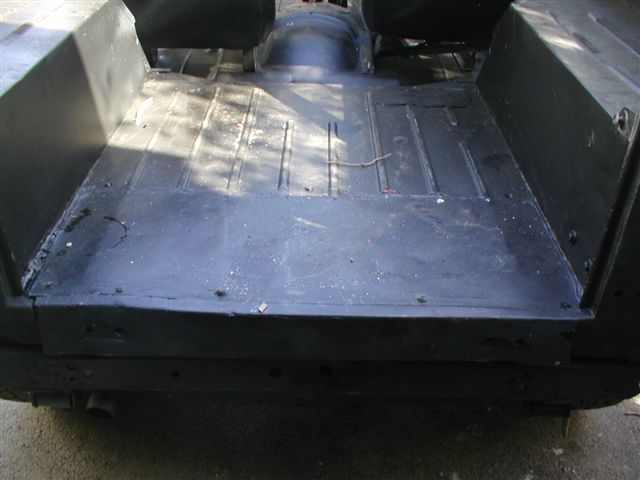 Rear interior floor of a vehicle, showing ribbed metal and black paint