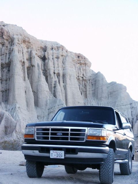 1996 Ford Bronco - A black Ford Bronco is parked in a desert landscape with unique rock formations in the background.