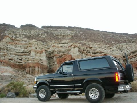 1996 Ford Bronco - This black 1996 Ford Bronco is seen parked in a desert area with distinctive rock formations in the background.
