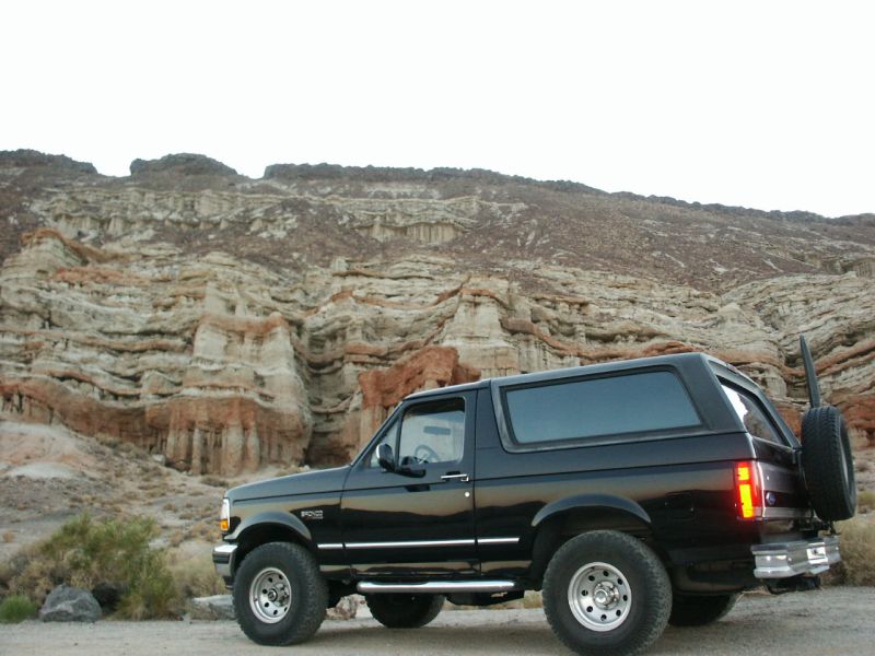 Black 1996 Ford Bronco parked in a desert landscape with rock formations