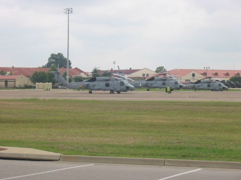 1988 Ford Bronco - Multiple helicopters are lined up on the tarmac at an airbase under a cloudy sky.