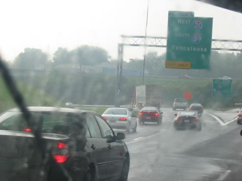 1988 Ford Bronco - Driving in heavy rain on the highway, with multiple vehicles and road signs visible.