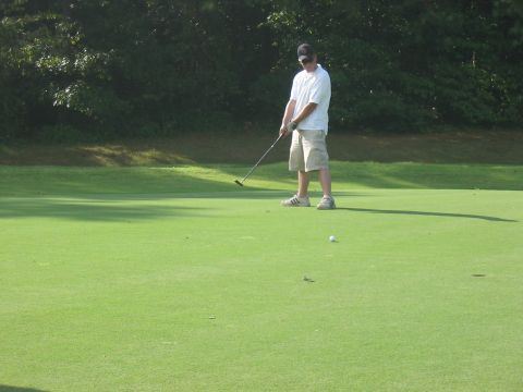1988 Ford Bronco - A golfer lines up a putt on a sunny day on the green.