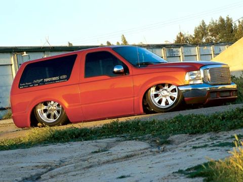 1993 Ford Bronco - This orange SUV features custom chrome wheels and a lowered suspension, with visible "Toyo Tires" branding on the rear window.