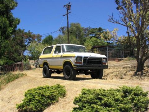 1978 Ford Bronco - A two-tone Ford Bronco sits parked on a dry, grassy hillside under a clear blue sky.