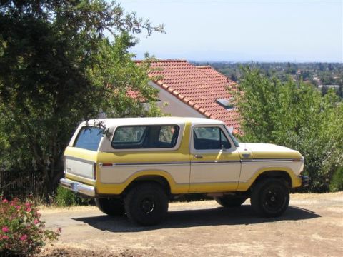 1978 Ford Bronco - A two-tone yellow and white 1978 Ford Bronco is viewed from the rear three-quarter angle.