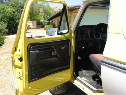1978 Ford Bronco - The interior of a yellow Ford truck is shown with the driver's door open, revealing the dashboard and interior details.