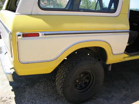 1978 Ford Bronco - The rear quarter panel of a yellow and white 1978 Ford Bronco shows its distinctive body style and chrome accents.