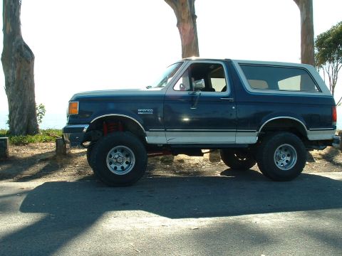 1990 Ford Bronco - Side view of a lifted 1990 Ford Bronco with a two-tone paint scheme.