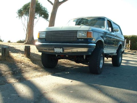 1990 Ford Bronco - This lifted 1990 Ford Bronco features a two-tone paint scheme and a prominent front grille.