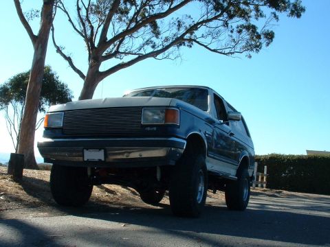 1990 Ford Bronco - This lifted 1990 Ford Bronco is parked outdoors under a tree.
