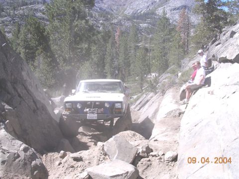 1994 Ford Bronco - A 1994 Ford Bronco navigates a challenging rocky trail with spectators watching from the side.