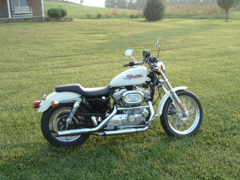 1995 Mercury Grand Marquis - A white Harley-Davidson Sportster motorcycle is parked on a grassy lawn with a house in the background.