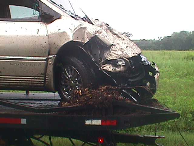 Wrecked silver Chrysler minivan with crushed front end on a flatbed tow truck