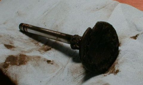 1990 Ford Bronco - A heavily soiled engine valve is shown on a stained cloth, indicating potential engine issues.