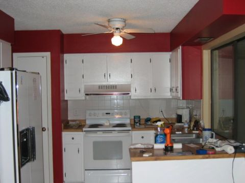 1985 Ford LTD Crown Victoria - A kitchen scene with white appliances and red accent walls.